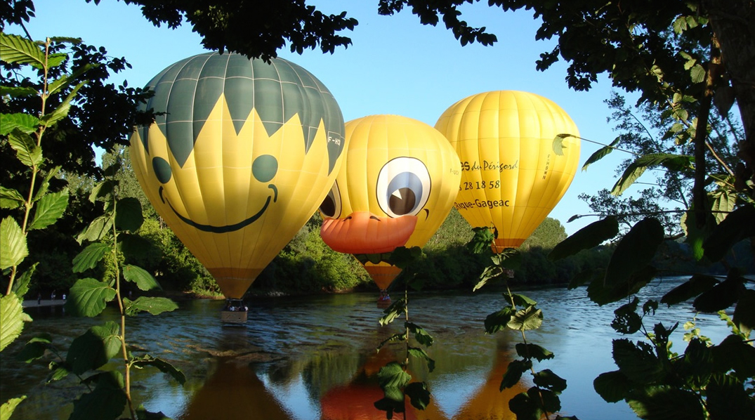 Photo de 3 montgolfières qui survolent la Dordogne