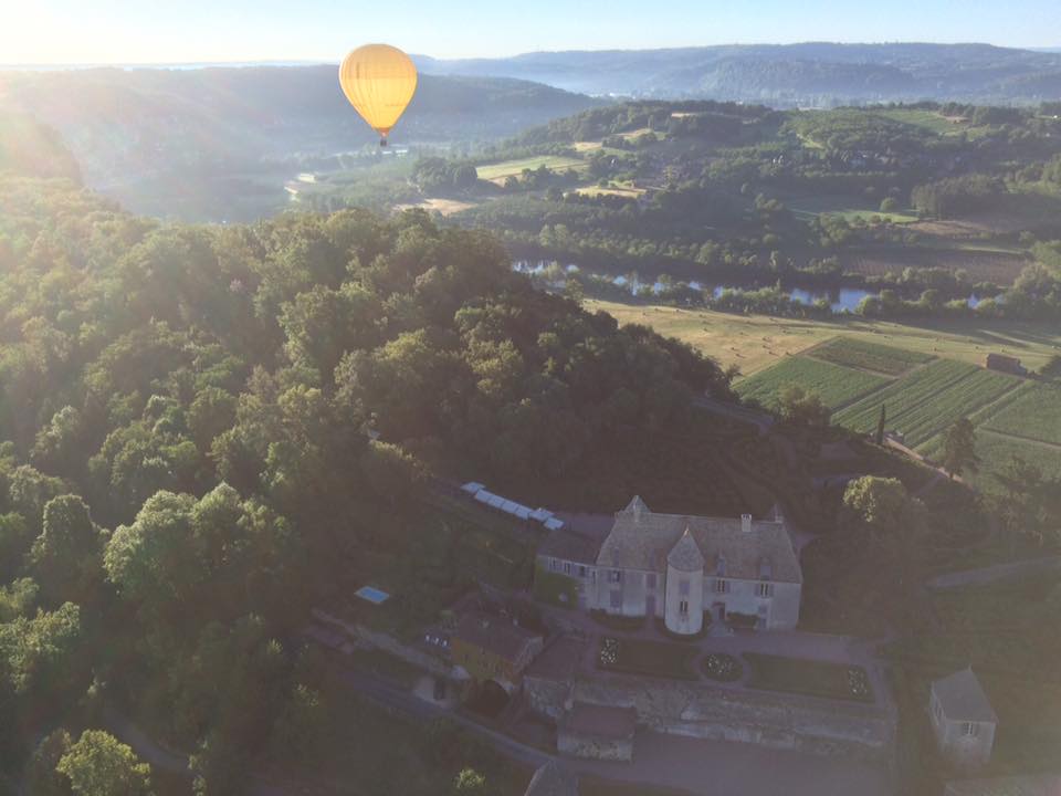 Photo représentant une montgolfière survolant le chateau de Marqueyssac et la vallée de la Dordogne