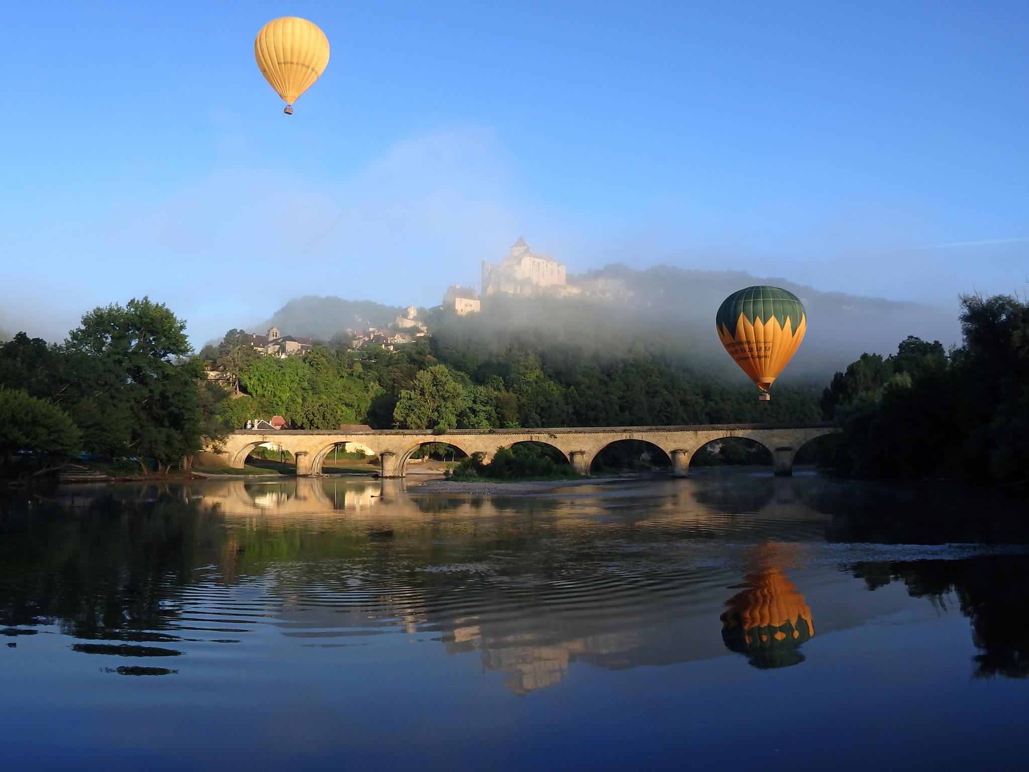 Photo représentant une contre-plongée sur des Montgolfières survolant la Dordogne à Castelnaud-la-Chapelle avec vue sur le chateau